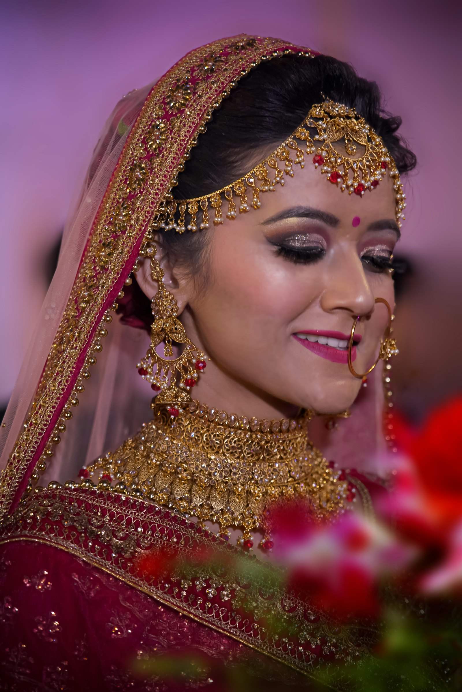 A bride in red and gold bridalwear with ornate jewellery