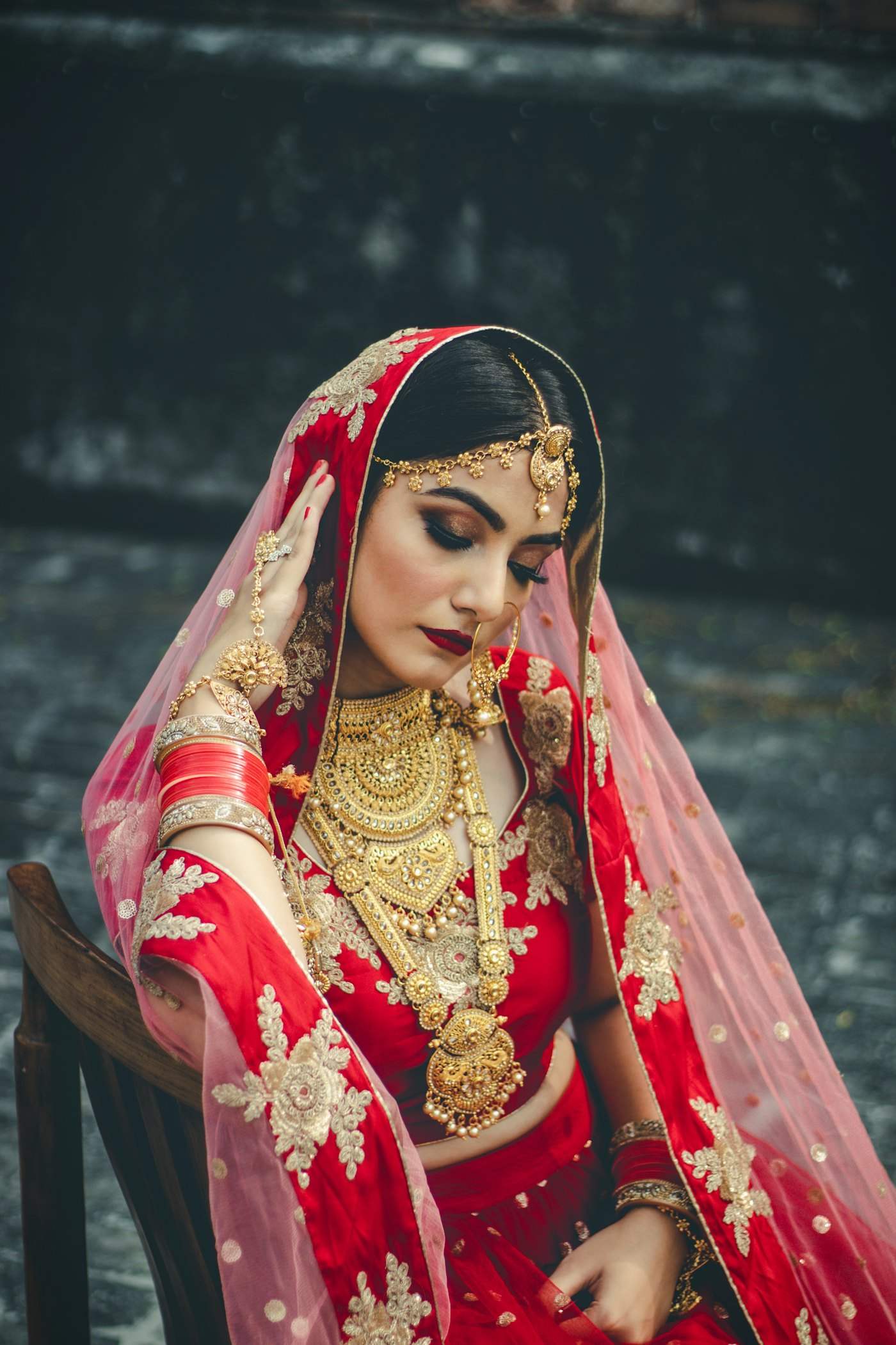 A bride in a red and gold wedding outfit with her hair styled up